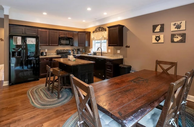 kitchen featuring a center island, light countertops, a sink, light wood-type flooring, and black appliances