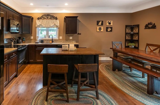 kitchen featuring light wood-type flooring, a center island, black range with electric stovetop, and a sink