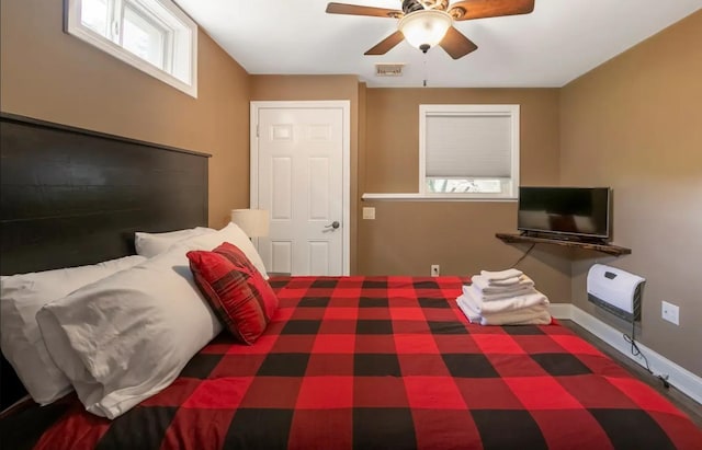 bedroom featuring baseboards, ceiling fan, visible vents, and heating unit