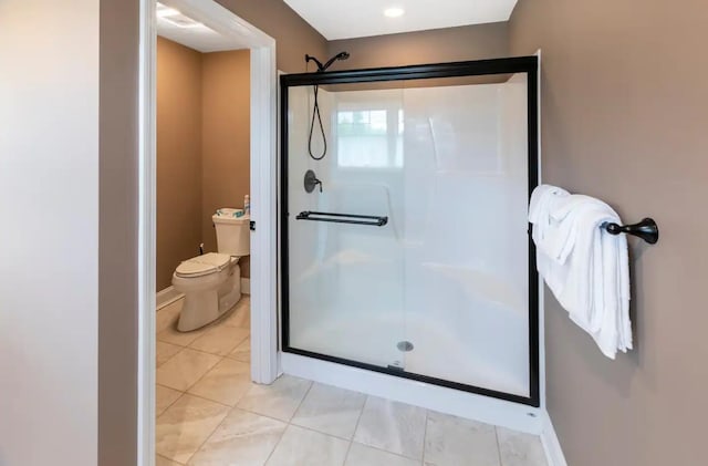 bathroom with tile patterned flooring, a shower stall, toilet, and baseboards