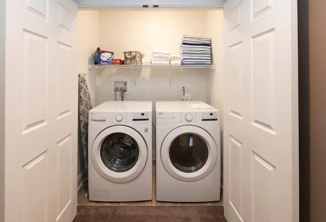 laundry room with laundry area, washing machine and dryer, and dark tile patterned flooring