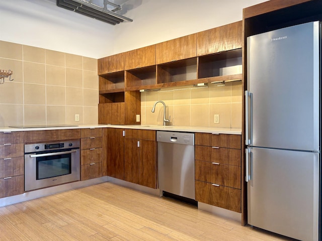 kitchen with light wood-style floors, light countertops, appliances with stainless steel finishes, backsplash, and open shelves