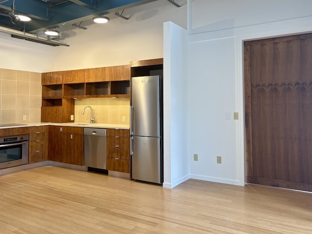 kitchen with light wood-style flooring, stainless steel appliances, light countertops, backsplash, and open shelves