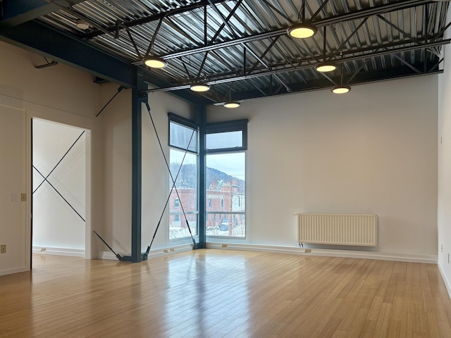 spare room with baseboards, radiator heating unit, and wood finished floors