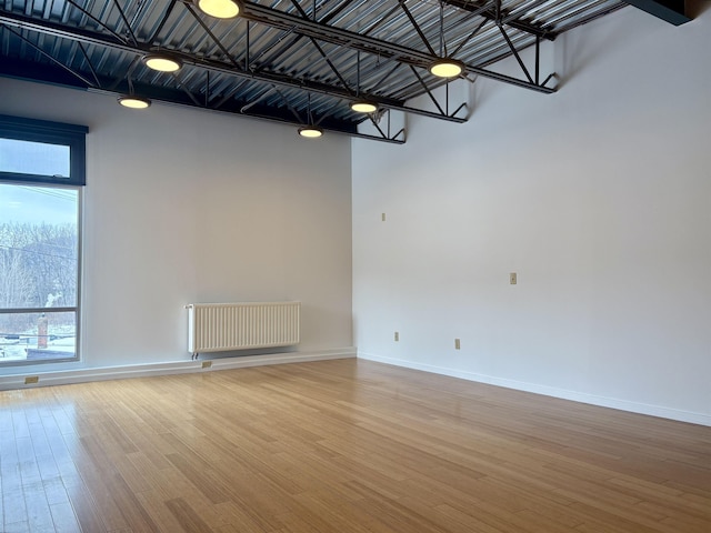 unfurnished room with radiator heating unit, baseboards, and wood finished floors