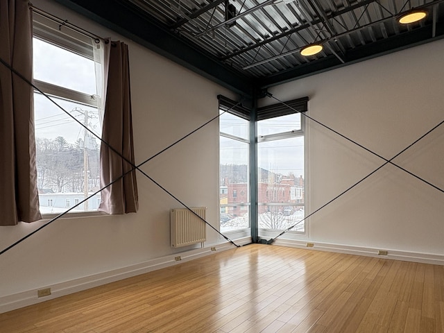 unfurnished room featuring a healthy amount of sunlight, light wood-style flooring, and baseboards