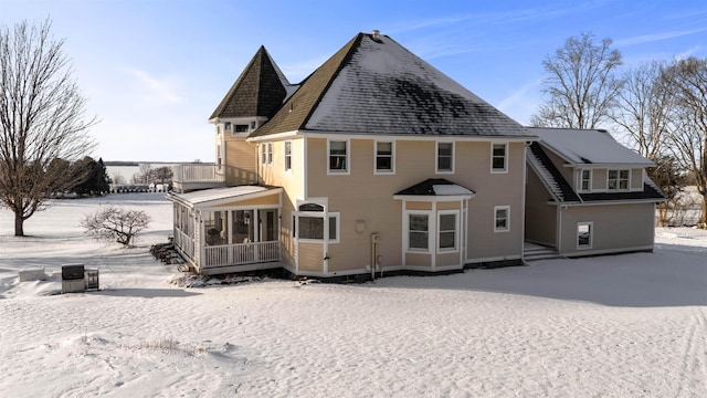 snow covered house featuring a sunroom