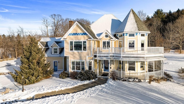 view of front of property with a balcony, a chimney, and a porch