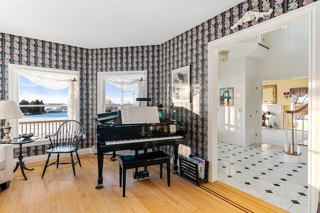 living area featuring wallpapered walls, baseboards, wood finished floors, a water view, and stairs