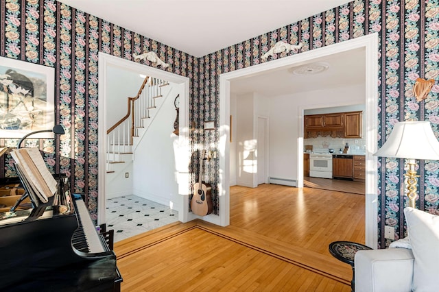 entryway featuring wallpapered walls, light wood finished floors, baseboards, stairs, and baseboard heating