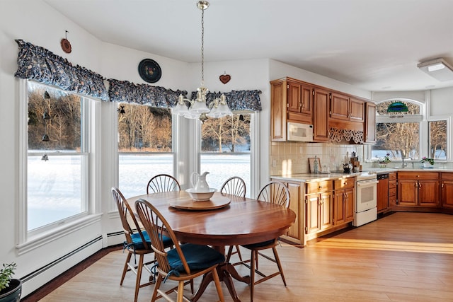 dining area with light wood-type flooring, a baseboard radiator, and a notable chandelier