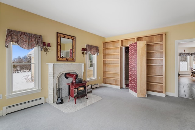 living area with a wood stove, carpet, a baseboard radiator, and a wealth of natural light