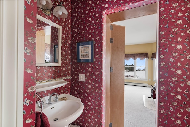 bathroom with a baseboard heating unit, a sink, and wallpapered walls