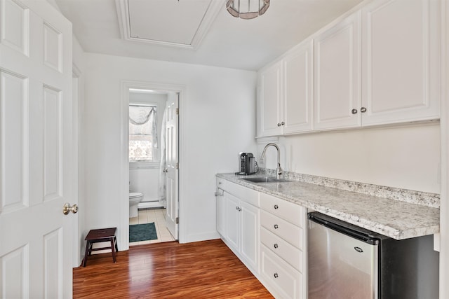 kitchen with light countertops, wood finished floors, a sink, and white cabinetry