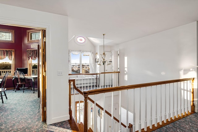 hallway featuring baseboards, lofted ceiling, an inviting chandelier, carpet, and an upstairs landing