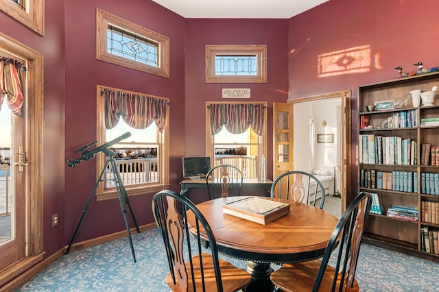 dining room featuring a high ceiling and baseboards