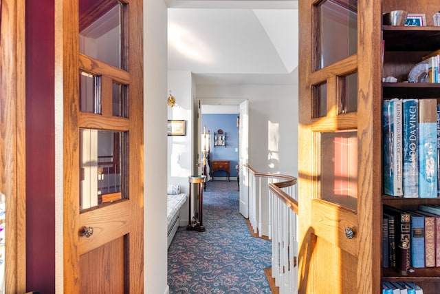 hall with dark colored carpet and baseboards