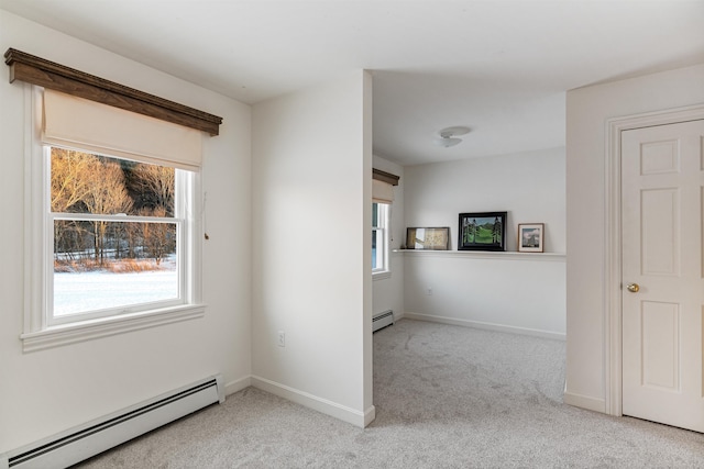 unfurnished room with a baseboard heating unit, baseboards, and light colored carpet