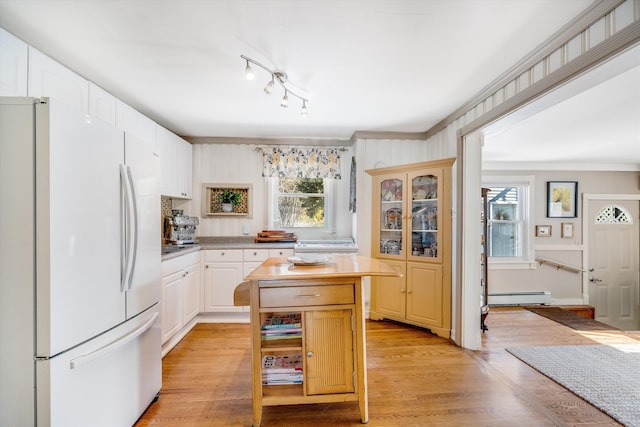 kitchen featuring white cabinets, a center island, freestanding refrigerator, baseboard heating, and light wood-type flooring