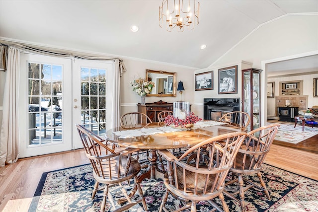 dining area with an inviting chandelier, ornamental molding, vaulted ceiling, and wood finished floors