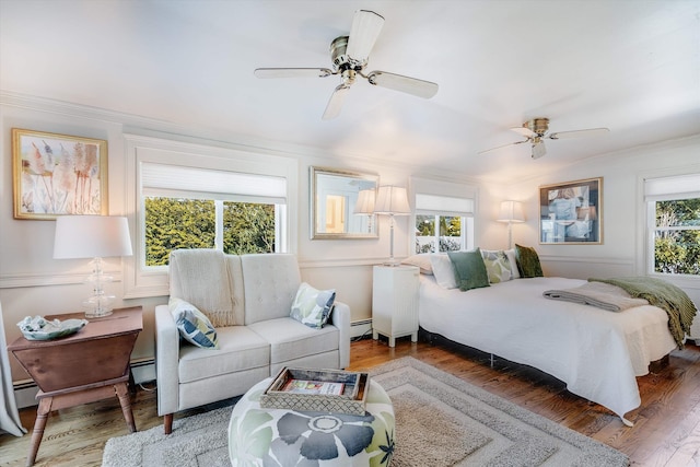 bedroom with a baseboard heating unit, a ceiling fan, ornamental molding, and wood finished floors