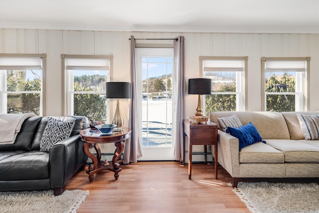 living room with a baseboard heating unit, crown molding, and wood finished floors