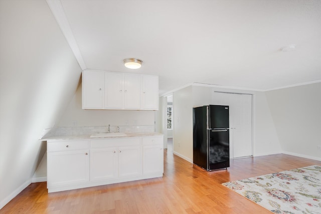 kitchen featuring white cabinets, freestanding refrigerator, light countertops, light wood-type flooring, and a sink