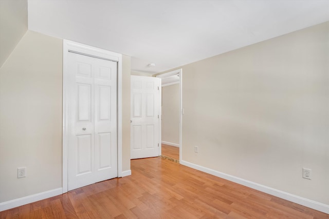 unfurnished bedroom featuring a closet, light wood-type flooring, and baseboards