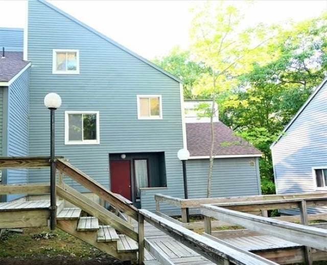 rear view of property featuring roof with shingles and stairs