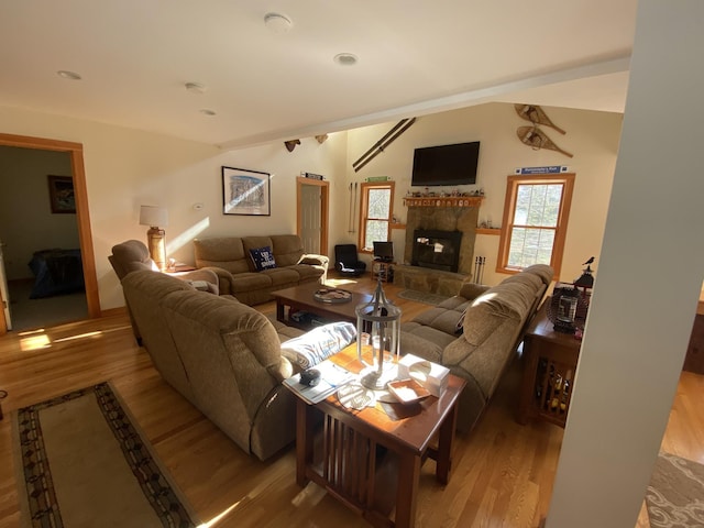 living area featuring vaulted ceiling, a fireplace, and wood finished floors