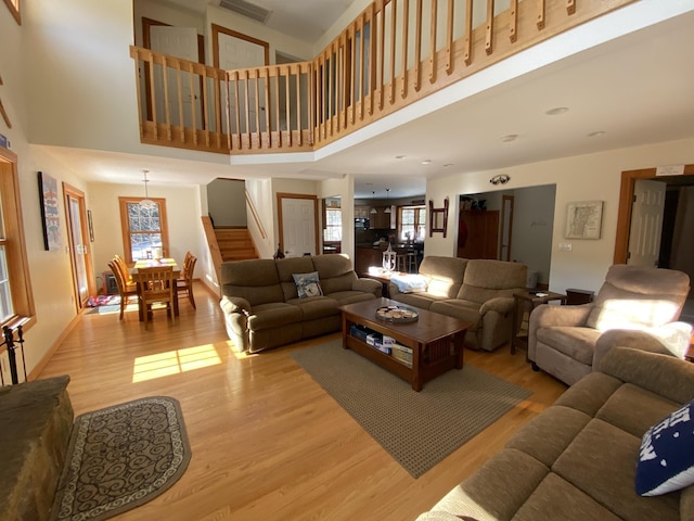 living area featuring light wood-type flooring, stairway, a high ceiling, and visible vents