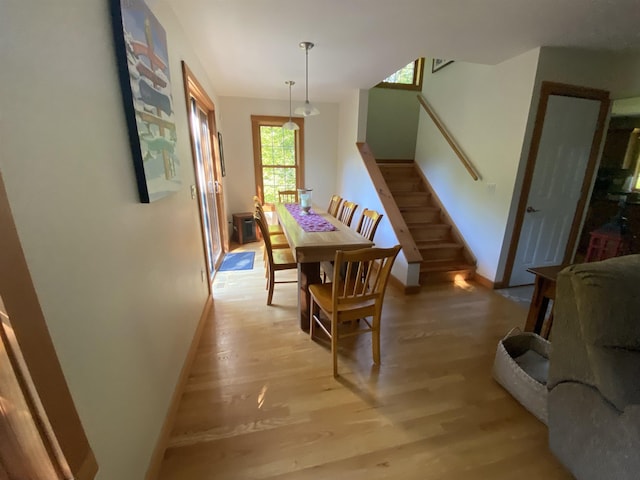 dining room with light wood-style flooring, stairway, and baseboards