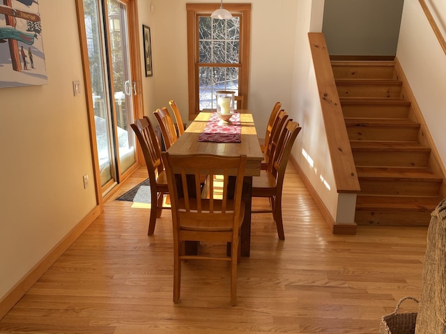 dining room with stairs, light wood-style floors, and a healthy amount of sunlight