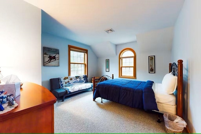 carpeted bedroom featuring vaulted ceiling, multiple windows, and visible vents