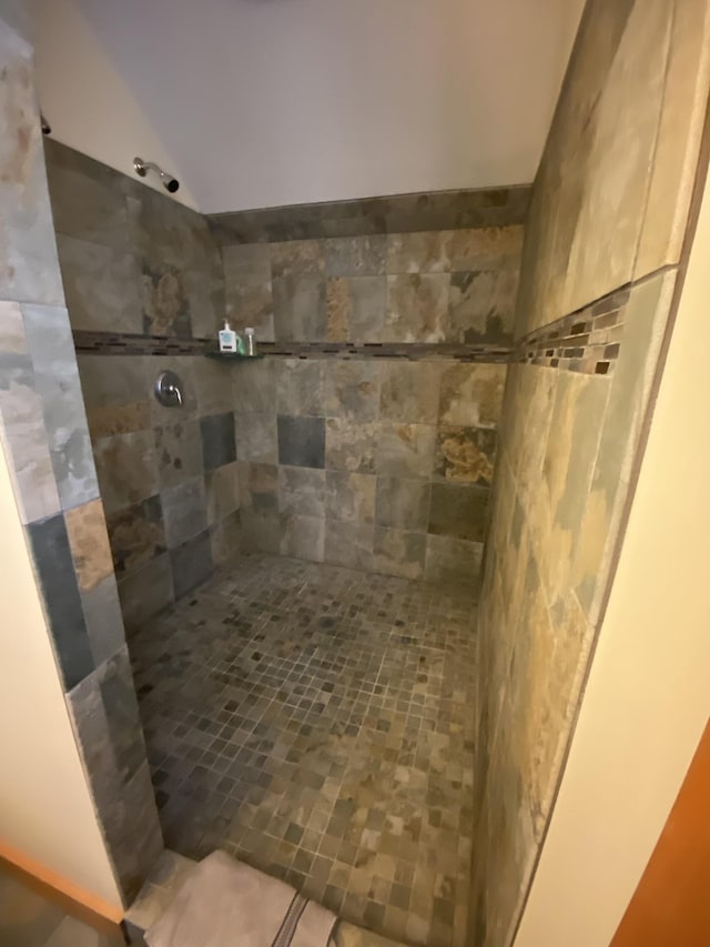 full bath with lofted ceiling and a tile shower