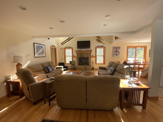 living room featuring light wood-type flooring, a glass covered fireplace, and baseboards