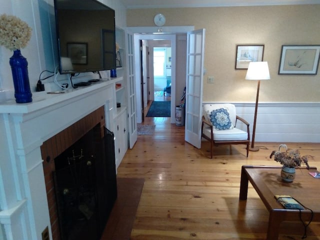 sitting room with a fireplace with flush hearth, wood finished floors, and wainscoting