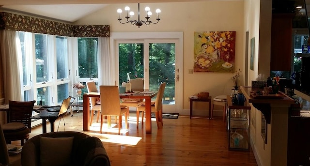 dining room featuring lofted ceiling, a notable chandelier, and wood finished floors