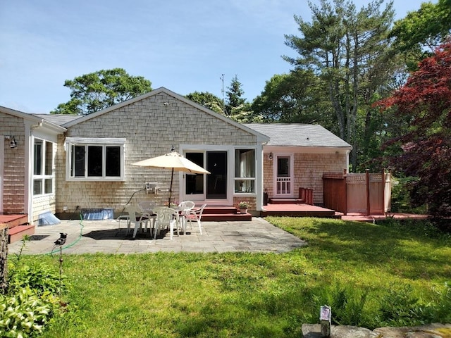 rear view of property with entry steps, a lawn, and a patio area