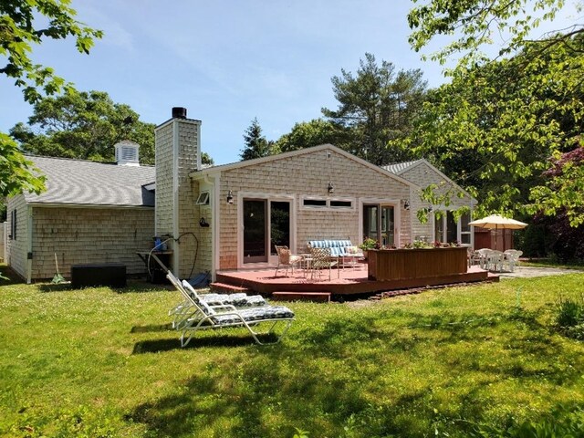 rear view of property featuring a deck, a yard, and a chimney