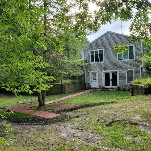 rear view of property featuring a yard, fence, and french doors