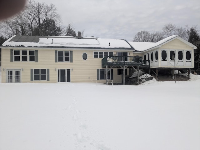 snow covered back of property with a chimney and a wooden deck