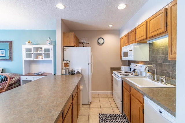 kitchen with light tile patterned floors, backsplash, brown cabinetry, a sink, and white appliances