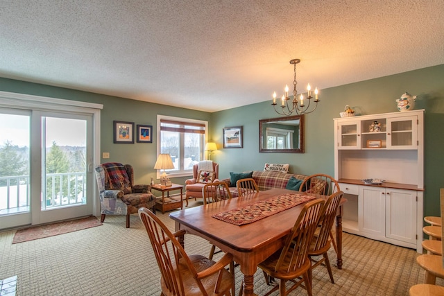 dining area featuring a chandelier, a textured ceiling, and light carpet