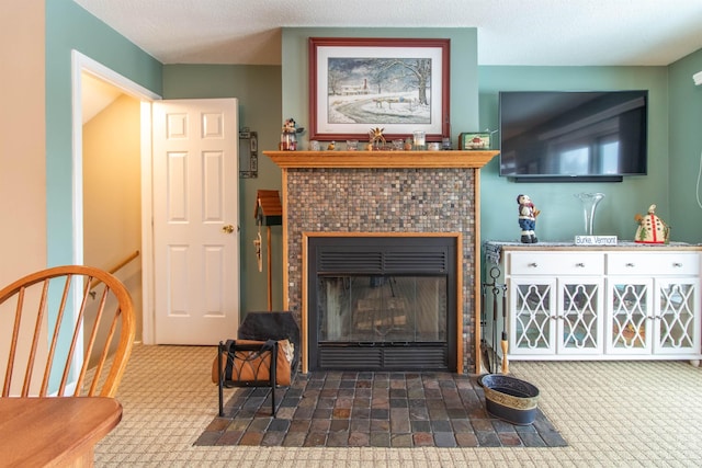 carpeted living room featuring a textured ceiling and a tile fireplace