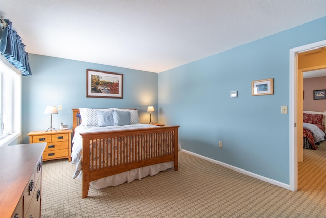 bedroom featuring light colored carpet and baseboards