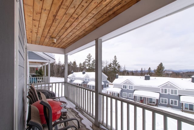 snow covered back of property featuring a sunroom