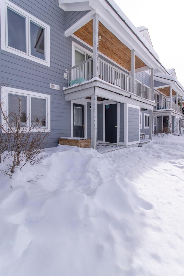 snow covered house featuring a balcony