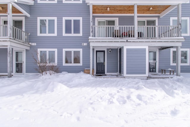 snow covered back of property with a balcony