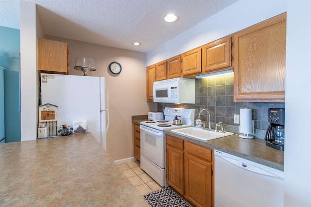 kitchen featuring a textured ceiling, white appliances, a sink, backsplash, and dark countertops